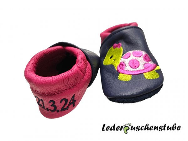 Lederpuschen dunkelblau-pink mit Namen links und Datums rechte Ferse dunkelblau sowie Stickerei Schildi 2 pink-rosa-hellgrün Schmetterlinge 
